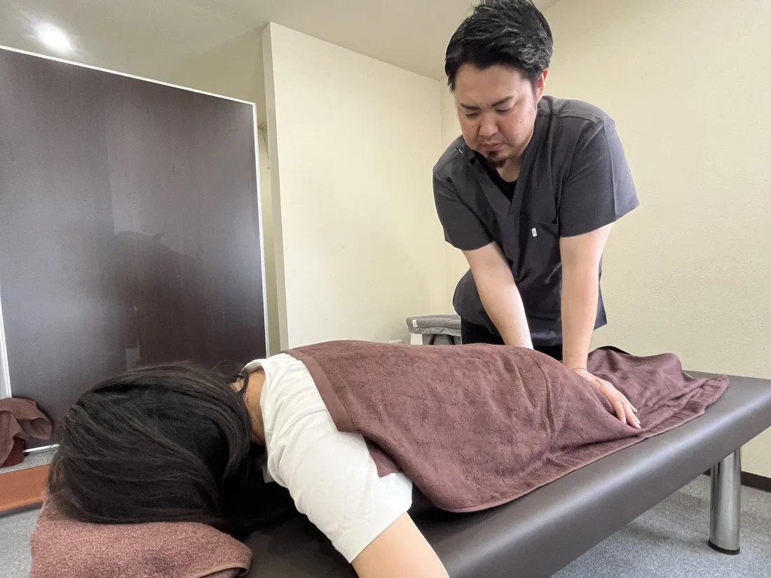 明るい院内で、院長がうつ伏せの方の背中を施術している様子
